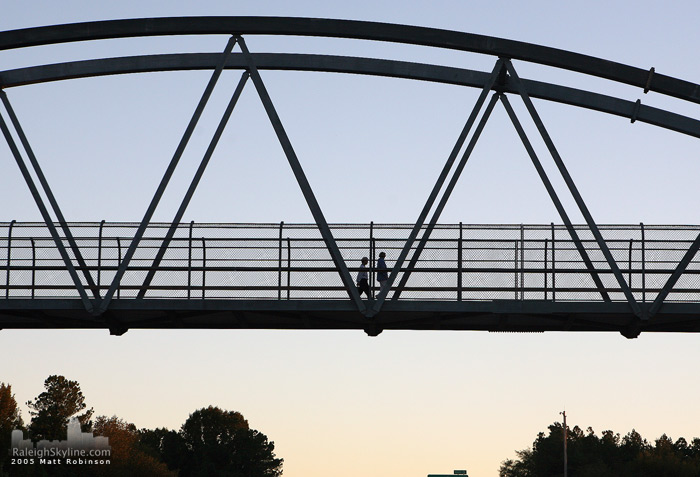 People walk across the Pedestrian Bridge over the I-440 Beltline.