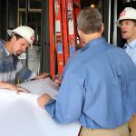 David Reynolds and unidentified men chat while looking at building plans for the Quorum Center.