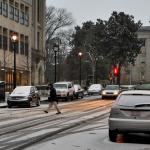 Snow rests on the North Carolina State Capitol dome as a man crosses the street.