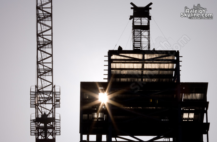 Construction workers await the first piece in the morning sun.