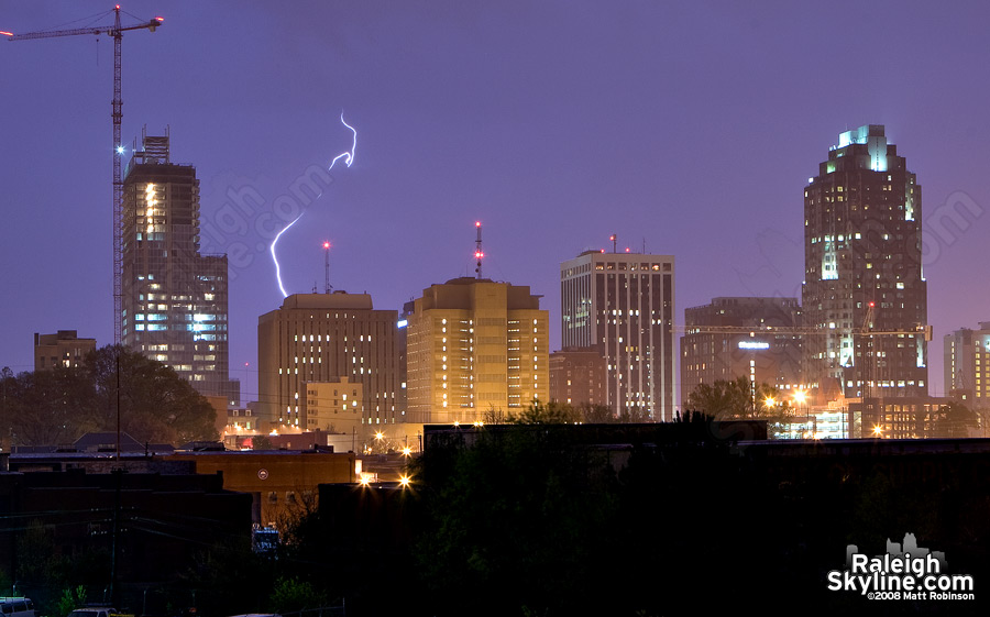 A more distant but intense strike behind the city, diffused by the rain.