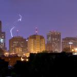 A more distant but intense strike behind the city, diffused by the rain.