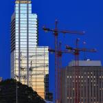 Three tower cranes for the new Wake County Courthouse reflect in RBC Plaza