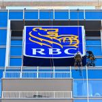 Two workers rappel to replace the RBC Plaza's sign