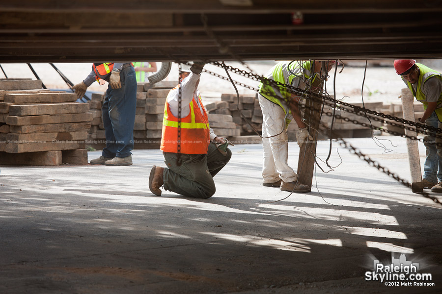 Workers check the platform on which the SunTrust Tower rolls into Raleigh