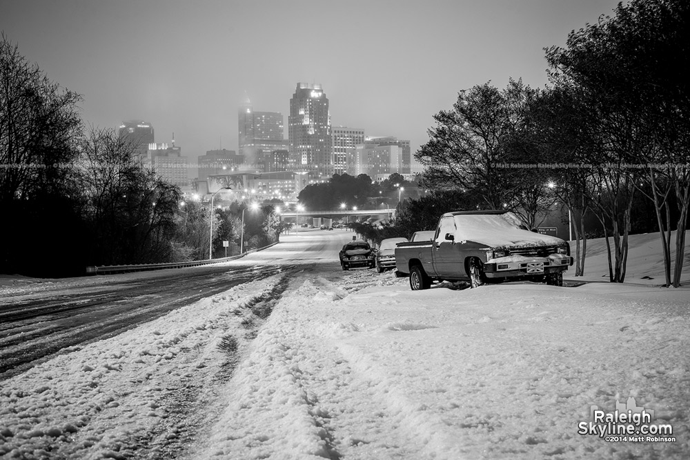 Black and White abandoned cars in the snow with Raleigh skyline