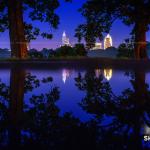 Downtown Raleigh and trees reflect in a another rain puddle at Dorothea Dix Park