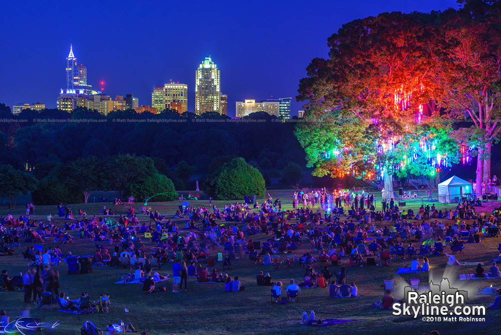 Downtown Raleigh looms over the crowds gathered to see the "Light the Woods with Sound" installation at Dorothea Dix Park