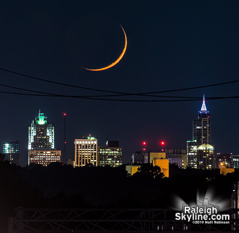 Setting crescent moon aligned behind Raleigh from 7 miles away.  Just 0.8% of the moon is illuminated.