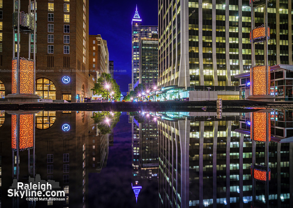 Downtown Raleigh reflecting in a large puddle on Fayetteville Street