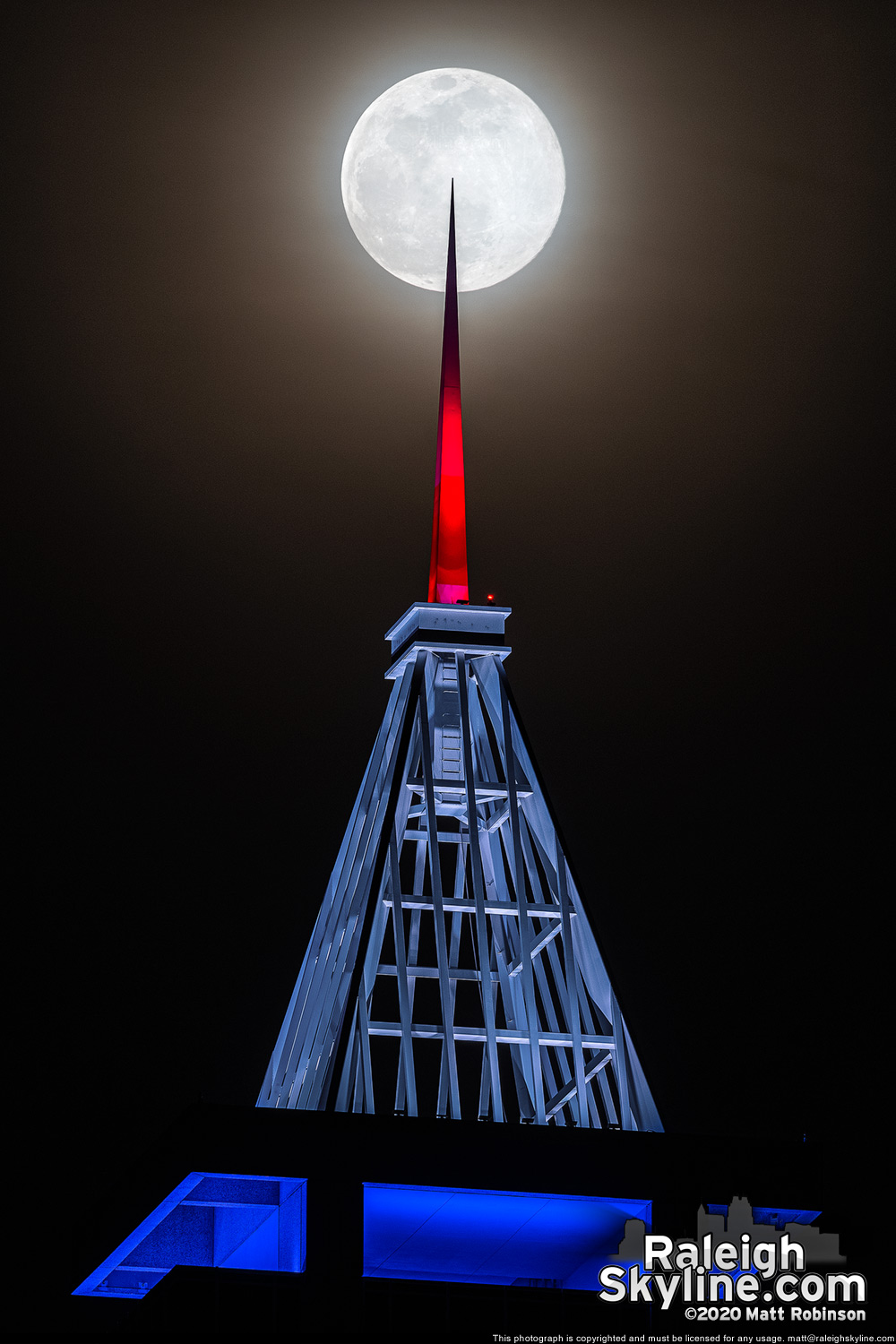 The "pink" supermoon is pierced by the red, white and blue lit spire of PNC Plaza