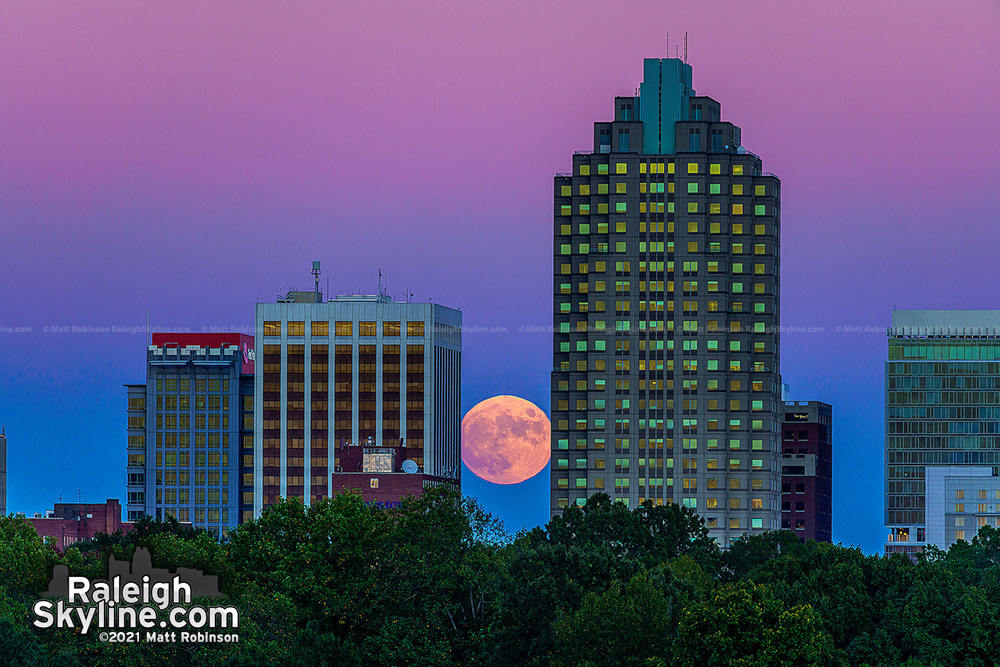 Moonrise caught between downtown Raleigh buildings One Progress Plaza and Two Hannover Square