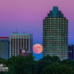 Moonrise caught between downtown Raleigh buildings One Progress Plaza and Two Hannover Square