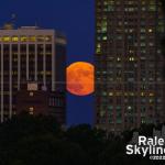 The moon rise caught between downtown buildings