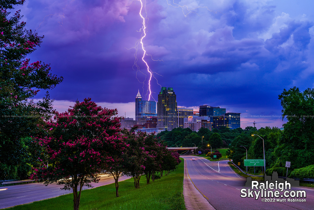 Single lightning bolt reaches from a storm to strike behind downtown Raleigh