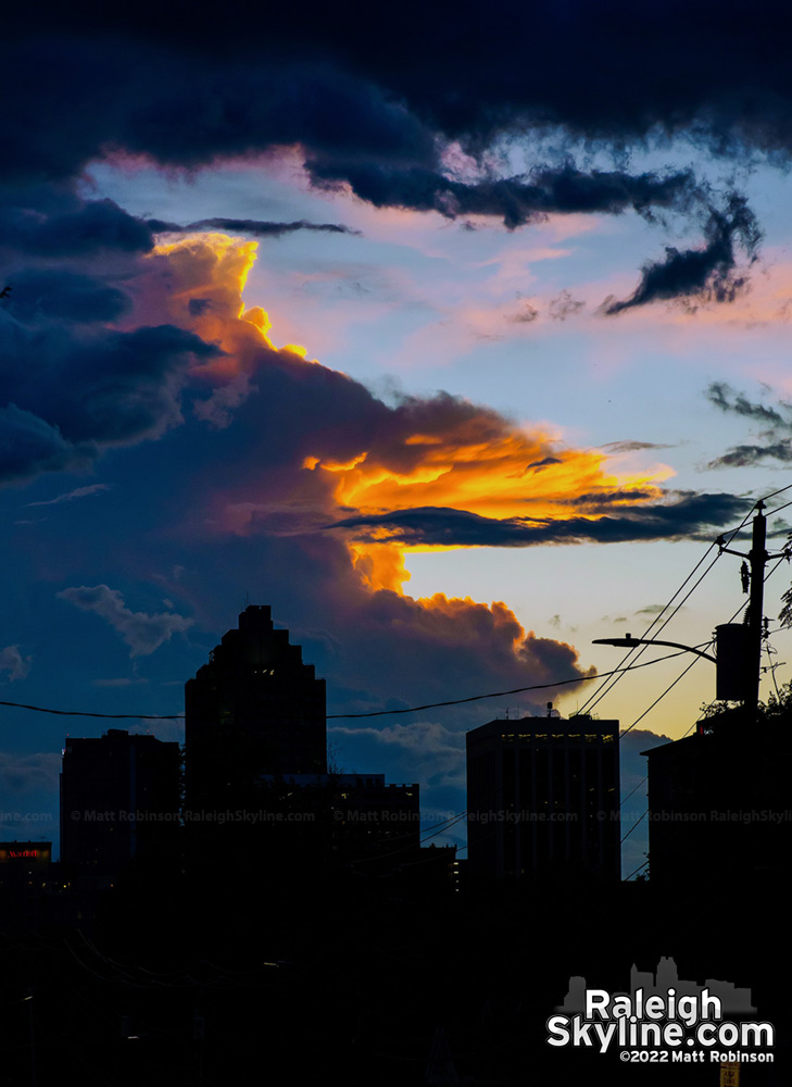 Distant thunderhead lit up at sunset behind downtown