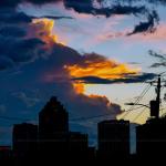 Distant thunderhead lit up at sunset behind downtown