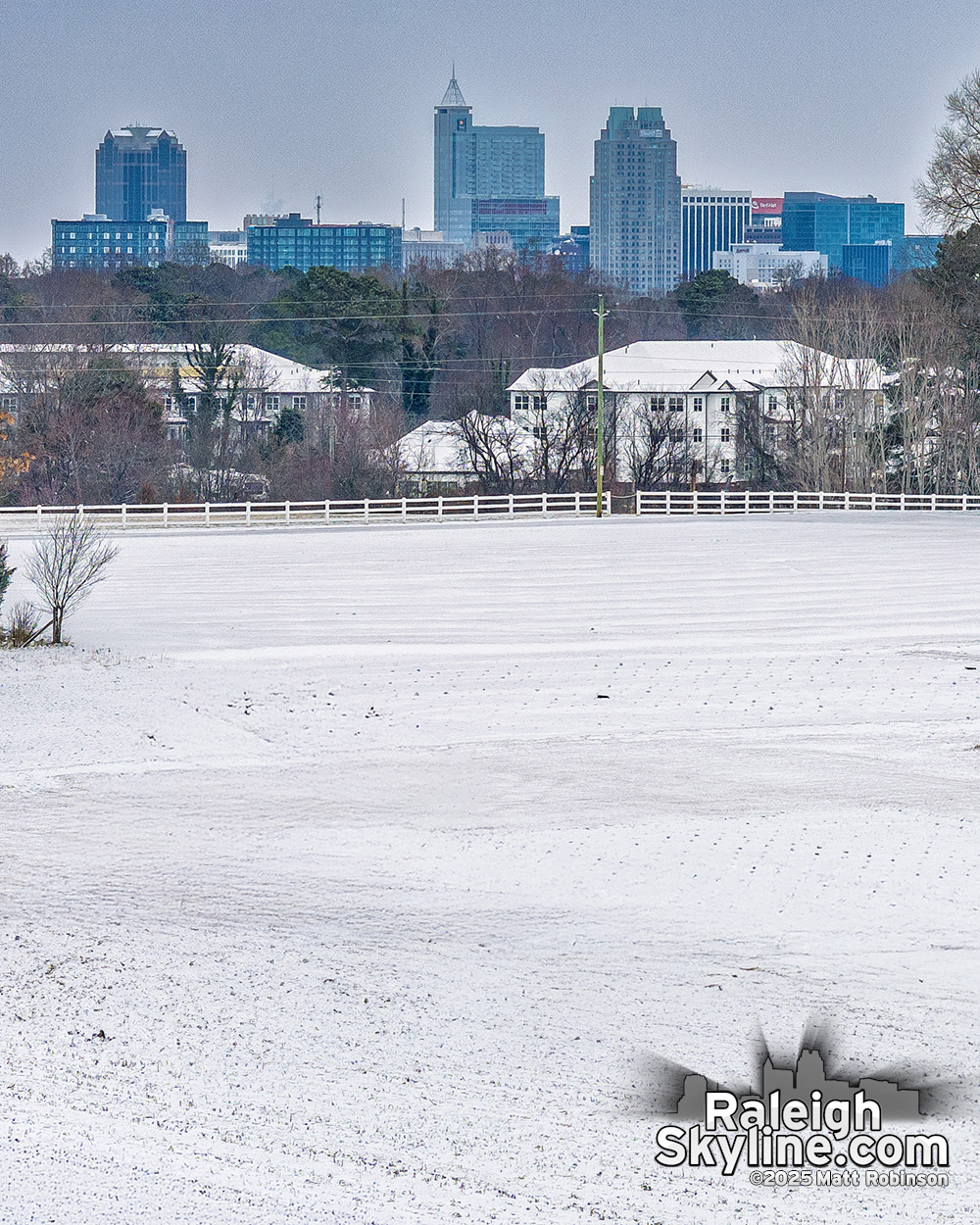 Snow covered NCSU fields along Lake Wheeler Road with downtown Raleigh