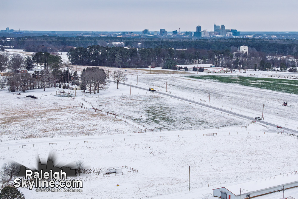 Snow covered NCSU fields along Lake Wheeler Road with downtown Raleigh